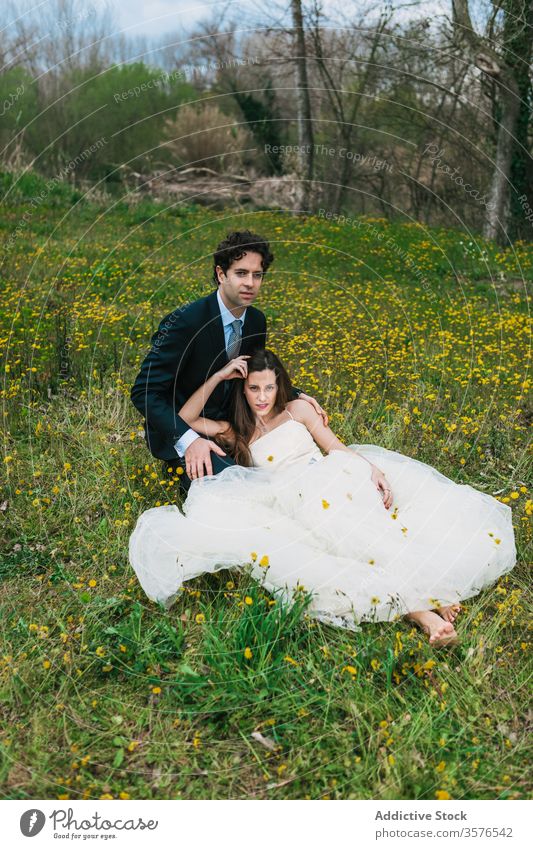 Newlyweds relaxing together in blossoming meadow newlywed couple wedding embrace bride groom flower lawn hug wedding day calm tranquil wedding dress serene