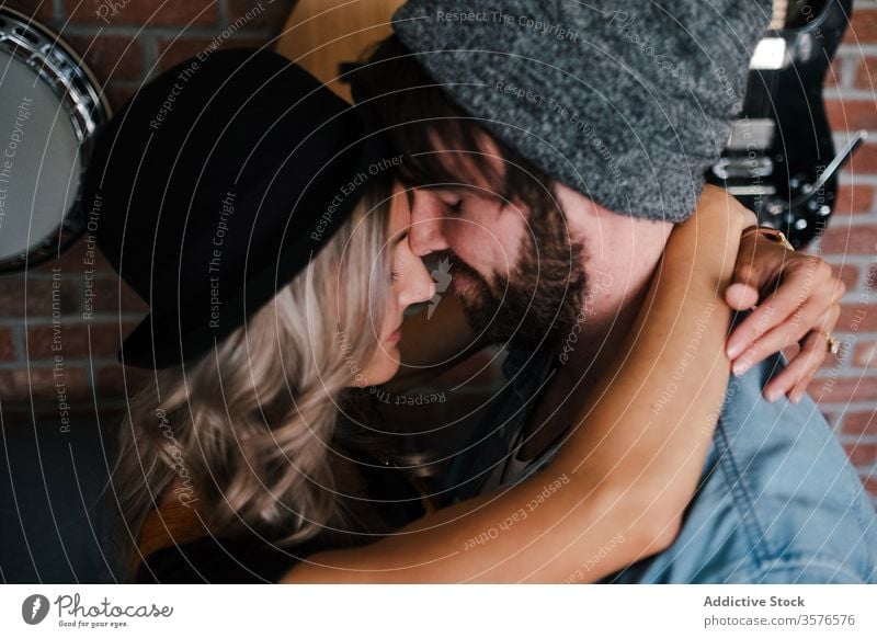 Couple embracing on sofa in apartment couple embrace kiss hipster loft relationship love interior musician boyfriend affection fondness together eyes closed