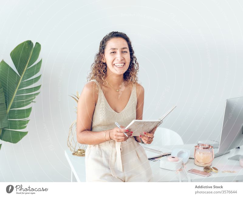 Cheerful woman reading notebook in office notes business smiling work table leaning female palma de mallorca spain style elegant trendy cheerful happy job