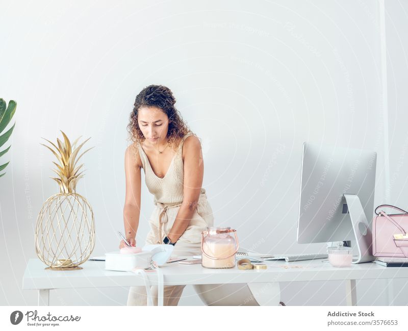 Businesswoman making notes in office writing notebook business smiling work table leaning female palma de mallorca spain style elegant data design decor light