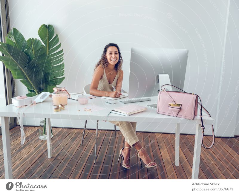 Smiling woman writing in notebook in office notes smiling leaves plant business work table leaning female palma de mallorca spain cheerful happy style elegant