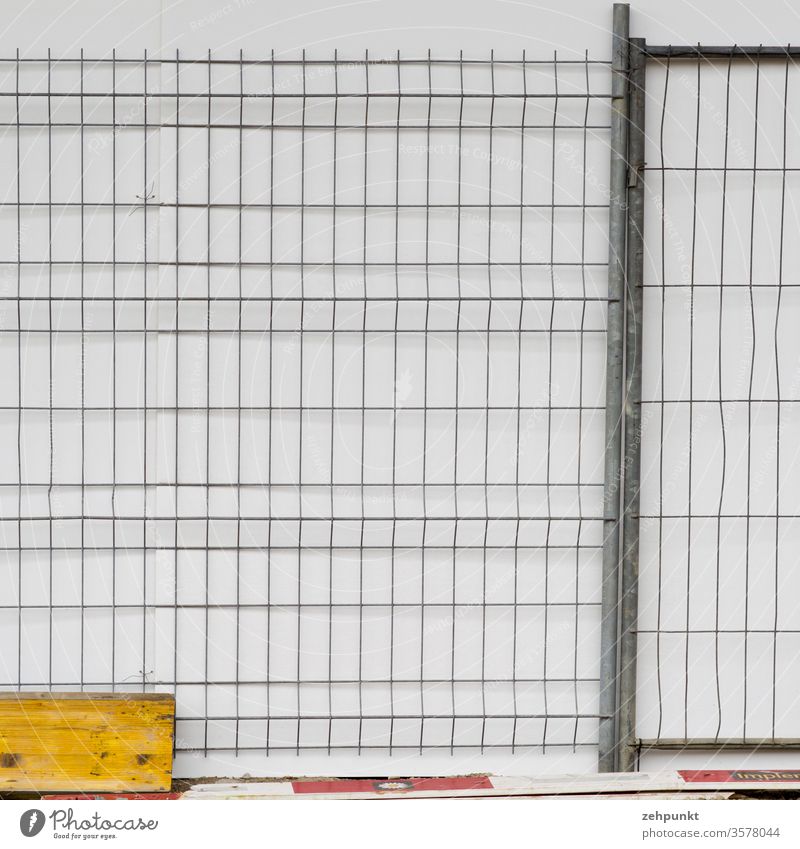 A building fence for white wall. On the ground are boards and barrier boards Hoarding At right angles Rectangles Grating Structures and shapes White Gray Yellow