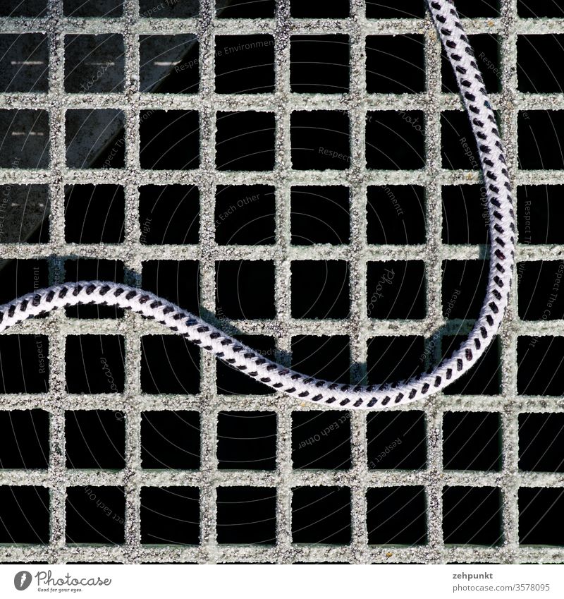 A rope snakes over a grating Dew End Rope Grating Metal grid jetty Curve meander lattice pattern Structures and shapes orthogonal boat port Harbour
