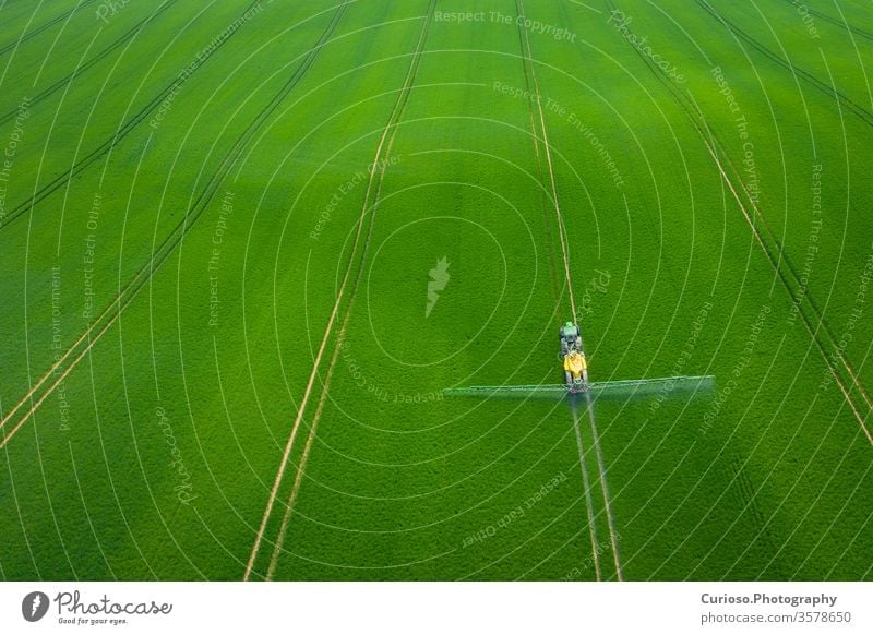 Green Fields. Aerial view of the tractor spraying the chemicals on the large green field. Agricultural spring background. fields above aerial agricultural