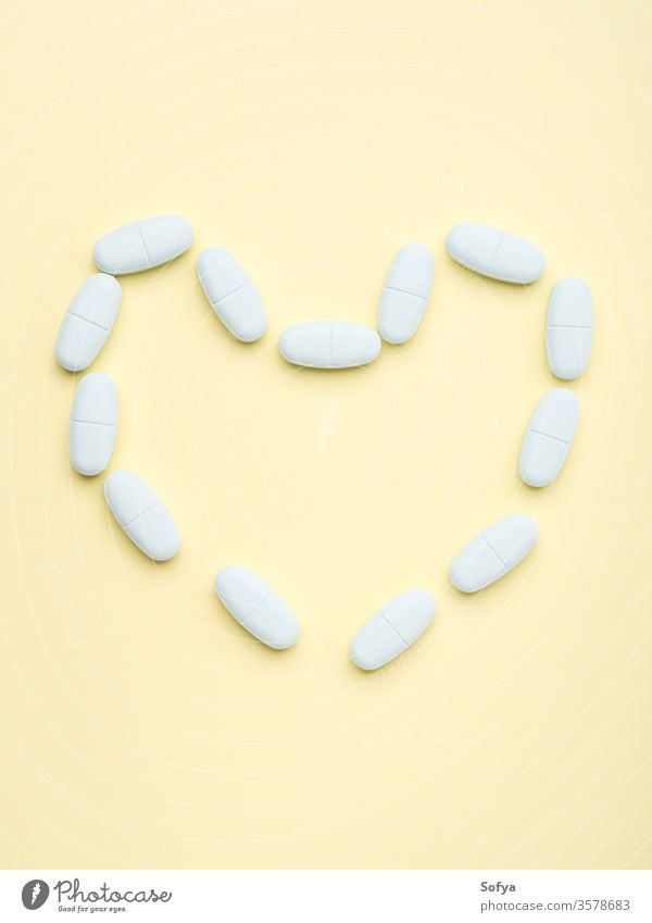 Blue pills forming heart shape on pastel yellow concept capsule dietary supplement healthy medicine tablet addiction antibiotic antioxidant beauty care disease