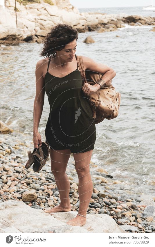 A beautiful female Latina carrying a bag and a slippers in the shore woman girl beauty young white pretty people attractive adult smiling happy portrait