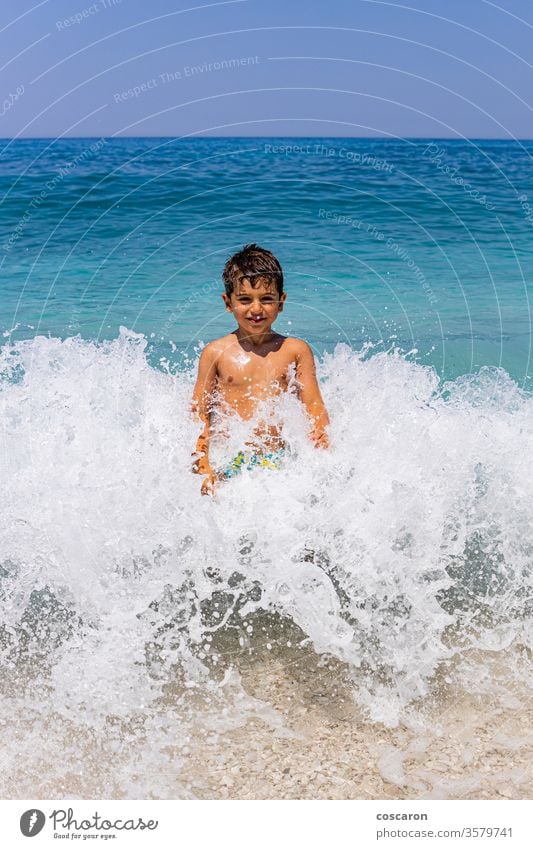 Funny kid in the middle of a giant wave active activity beach beautiful boy caucasian child drop emotion emotional enjoying enjoyment face female foam fun