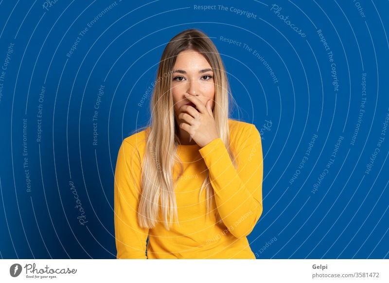 Blonde girl wearing a yellow T-shirt person blue blonde scaredy-cat scary intimidate mute mouth cover fair hair head expression gesture young beautiful female