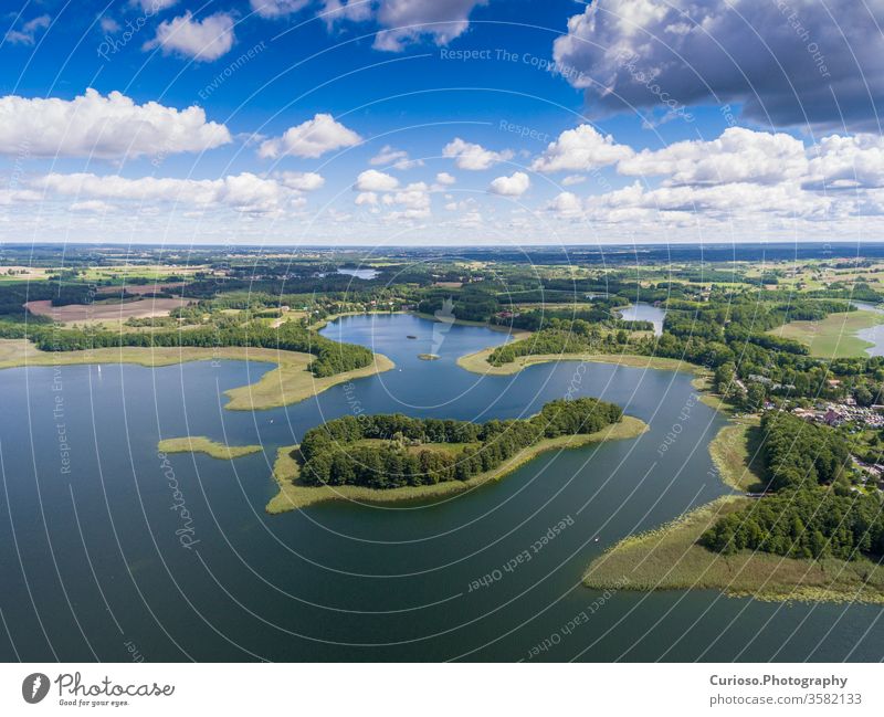 View of small islands on the lake in Masuria and in the district of Podlasie, Poland. Blue water and white clouds. Summertime. View from above. Helicopter