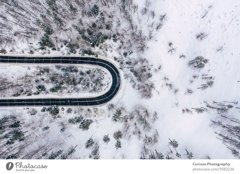 Curvy windy road in snow covered forest, top down aerial view. Winter landscape. winter drone above nature snowy white tree background season ice scenic cold