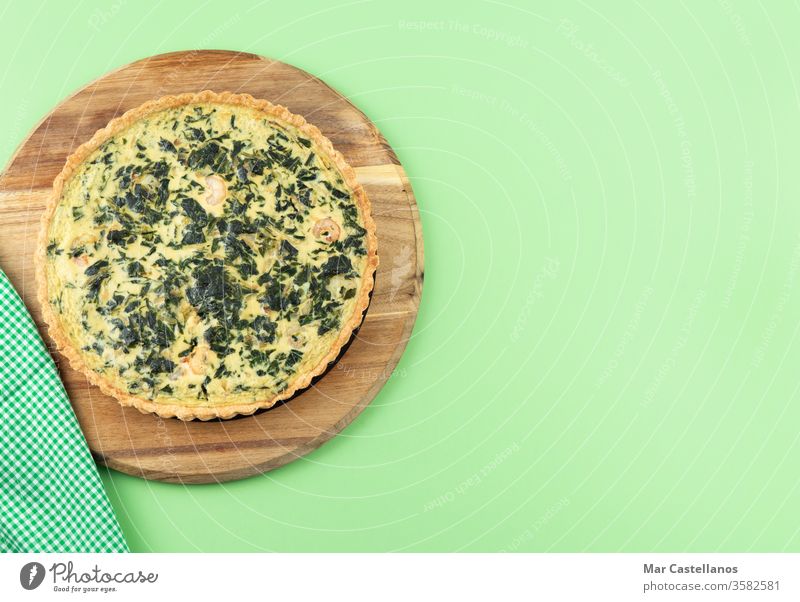 Vegetable quiche on a green background. Copy space. Quiche vegetables spinach kitchen table copy space top view food cheese baked meal lunch dinner homemade