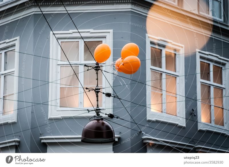 A group of balloons are attached to an overhead line Balloon Movement To hold on Fixed Facade House (Residential Structure) house wall cross Wall (building)