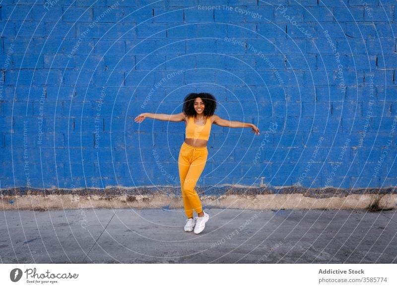 Cheerful African American woman with afro hairstyle in dancing pose dance move vivid vibrant cheerful smile motion color female black ethnic african american