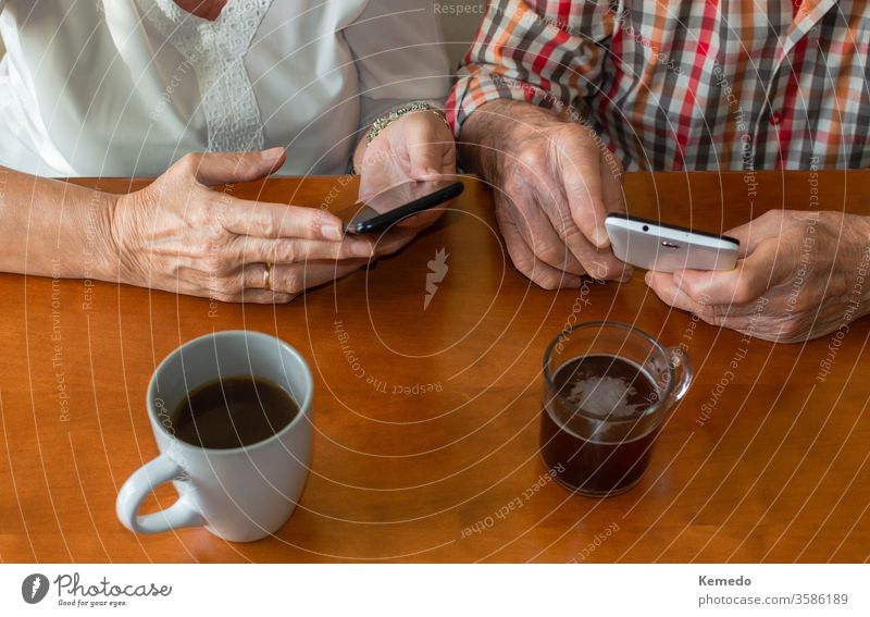 Top view of old people using smartphones at home while enjoying cups of hot drinks. Concept of elderly people and technology. senior mobile use happy person