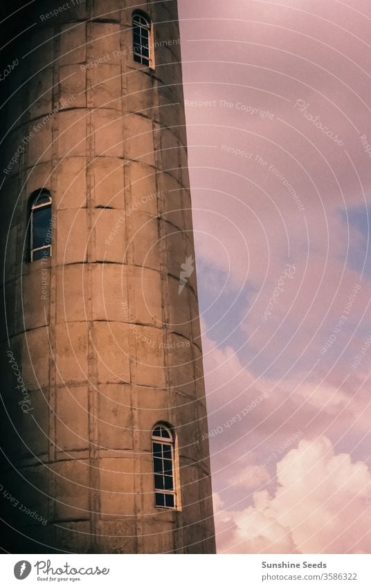 Partial view of an old water tower made from bricks town city vintage art deco retro windows architecture building blocks pink purple reserve grunge tank sky