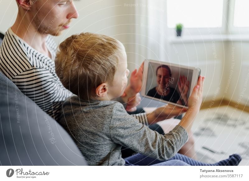 Father and son having video call to mother family internet technology modern people home chat computer communication woman young happy online wireless