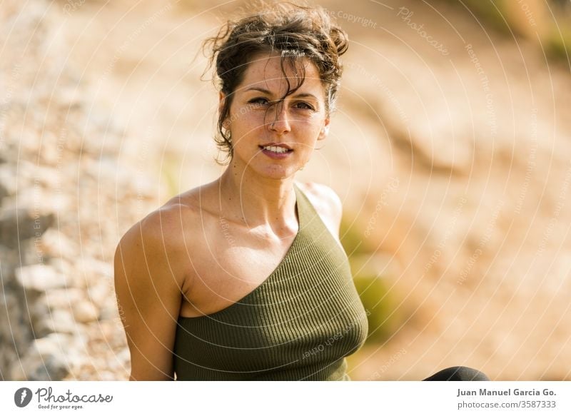 A selective focus shot of a beautiful female Latina sitting on the rock woman girl pretty beauty young white black adult portrait attractive people caucasian