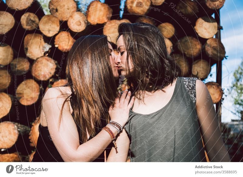 Young lesbian couple kissing women rustic wall log summer same sex summertime daytime young tender homosexual lgbtq gay lifestyle love relationship lover stand