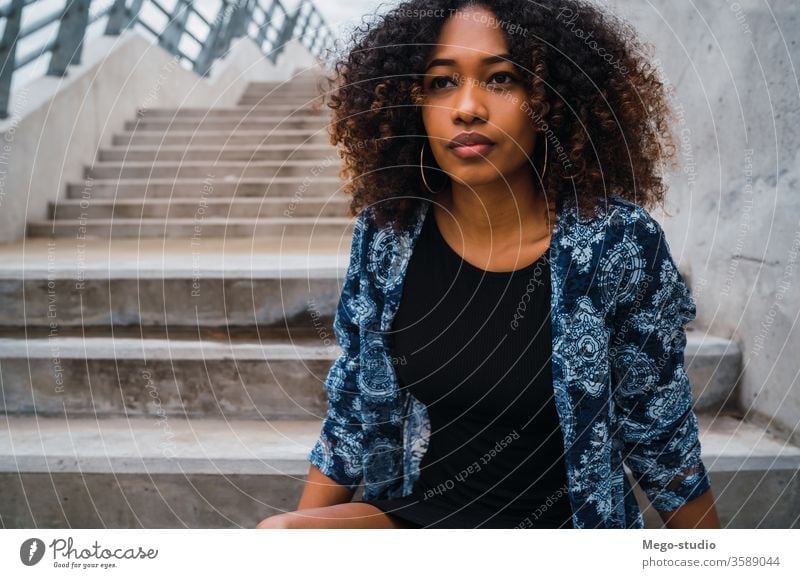 Afro-american woman sitting on steps. afro grey young girl face wall expression adult looking fashion black standing smiling confident hair brunette model