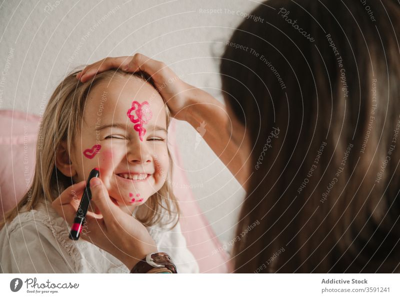 Cute girl with painted face sister having fun weekend play pastime color home sibling together playful relationship kid teen little childhood cute teenage