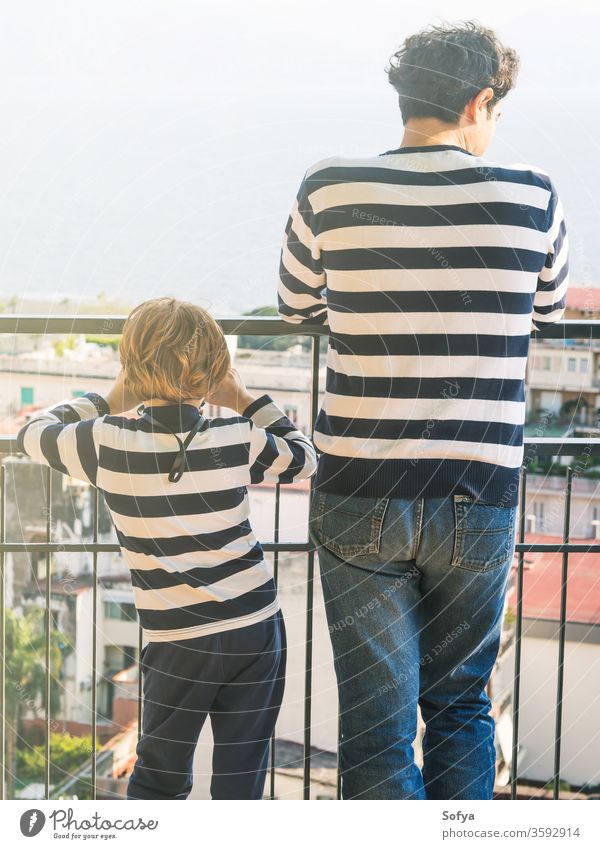 Father and son wearing striped shirts father fathers day authentic together caucasian family love boy kid city balcony celebrate candid real look urban watch