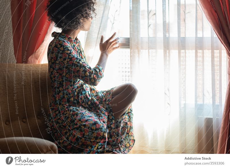 Pensive black woman in dress near window in living room pensive rest armchair calm relax peaceful style female ethnic african american afro harmony hairstyle