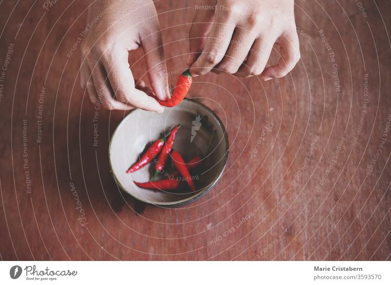 Close up of hands preparing red chilies for cooking to show concept of gastronomy, cuisine, clean and healthy eating and Ayurveda cooking conceptual background