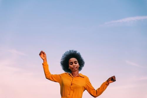 black woman dancing with the wind outdoors blue sky girl young people portrait lifestyle cool lovely garden yellow flower exterior nature afro hair
