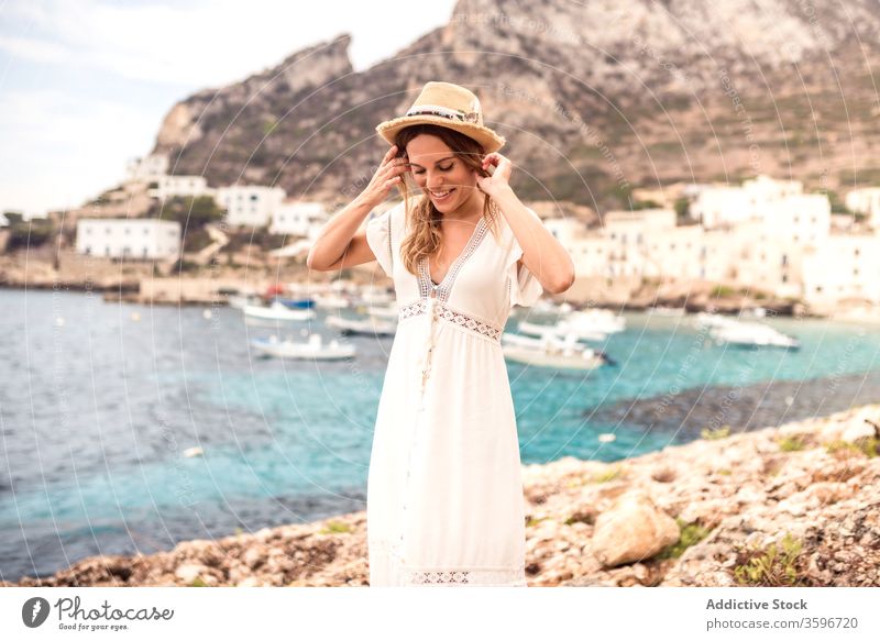 Delighted traveling woman on stone parapet in bay vacation harbor traveler delight tourist stand holiday boat female levanzo island summer happy fence smile