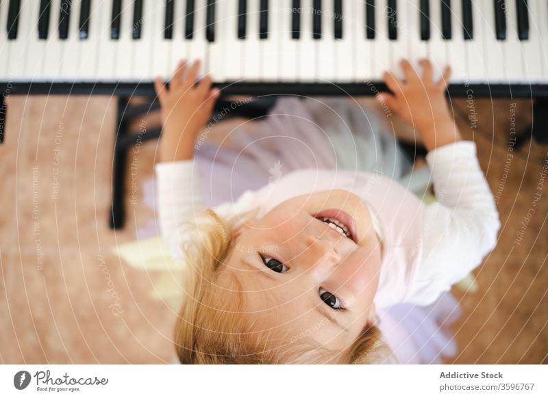 Laughing girl playing piano looking up at camera home synthesizer fun laugh happy study smile childhood toddler cute music class skirt schoolgirl education