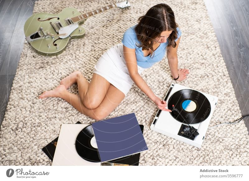 Young woman listening to music on vinyl disc record player home rest retro meloman young female sound melody song audio tune hobby device entertain lifestyle
