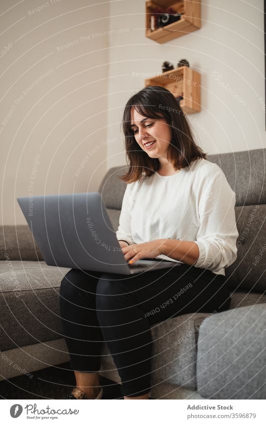 Female freelancer using laptop at home multitask entrepreneur woman smile gadget happy project browsing female confident sofa remote device work internet