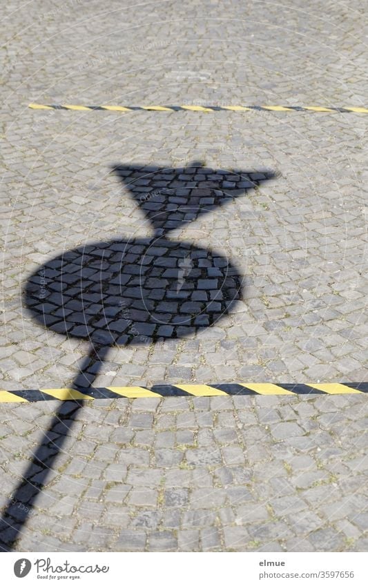 Shadow of a traffic sign on a paved road and two black and yellow markings for keeping distance gap keep sb./sth. apart Road sign Protection against infection
