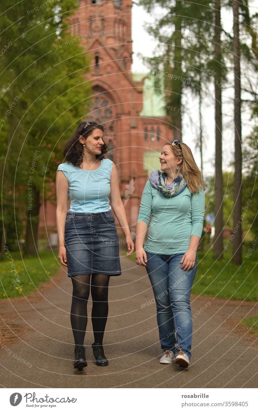 vital | friendship - two young women are walking and talking, in the background a church girlfriends To go for a walk Friendship maintain togetherness