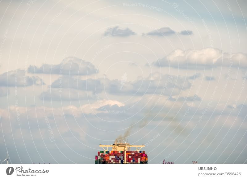 the containers on a cargo ship smell the yellow smoke rising from the chimney| minimalistic partial view of a container ship in cloudy weather Container
