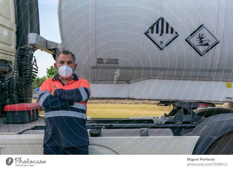 Truck driver with face mask posing next to a dangerous goods tank truck truck driver man trucker high visibility adr cabin fuel liquid transport veteran