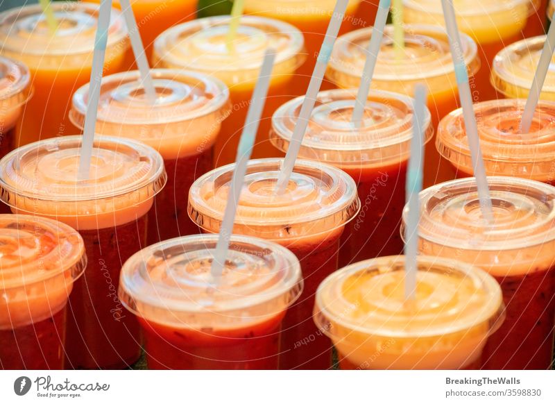 Many plastic glasses of fresh juices and smoothies Juice many disposable straw drinking closeup high angle view beverage healthy eating lifestyle row retail