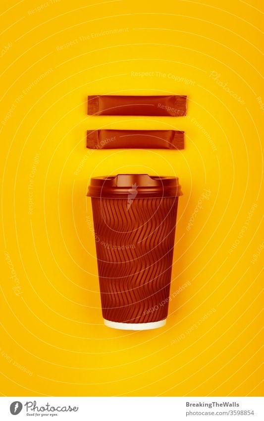 Brown paper coffee cup over yellow Coffee tea disposable brown dark one cap vivid stick sachet two sugar background closeup hot drink beverage takeaway copy