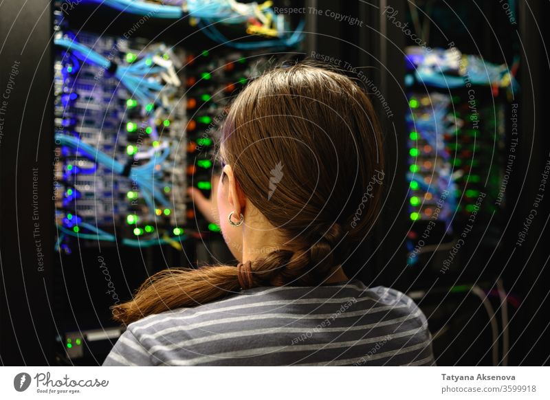 Woman networking engineer near working server rack technology data woman center internet system connection cable hardware business professional computer digital