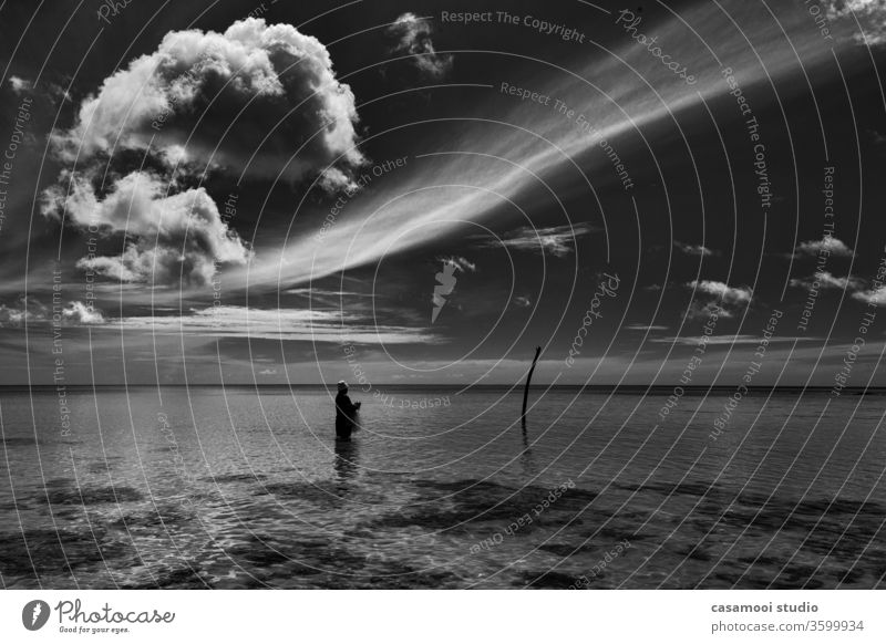 black and white fisherman in the ocean in search of fish under the clouds Clouds Clouds in the sky Nature Man Black & white photo Food Search Ocean Rain