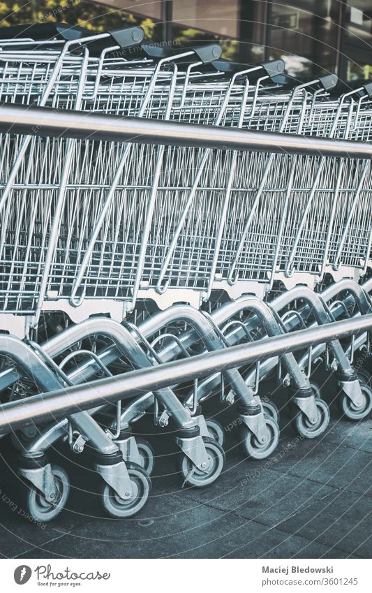 Row of empty shopping carts. supermarket retail row trolley store buy basket business grocery consumerism metallic purchase chrome object concept line symbol