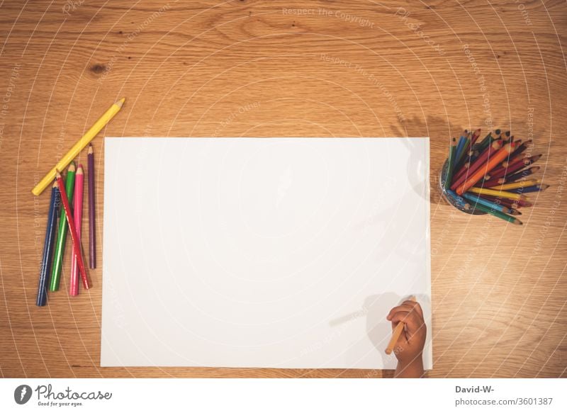 Child holds a crayon in his hand in front of a white sheet of paper crayons pens colors colourful Painting (action, artwork) creatively Creativity flaked