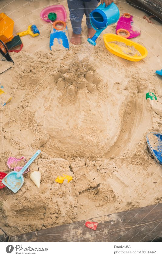 Child playing in the sandbox plays Sandpit Toys fun Joy self-employment Employment Anonymous Cast Water Wet Watering can sandy Garden Playground Playing