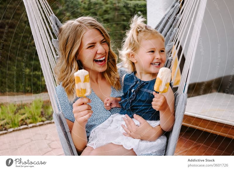 Happy little girl and woman with homemade popsicles mother daughter hug lolly ice enjoy cheerful summer terrace smile ice cream toddler female together