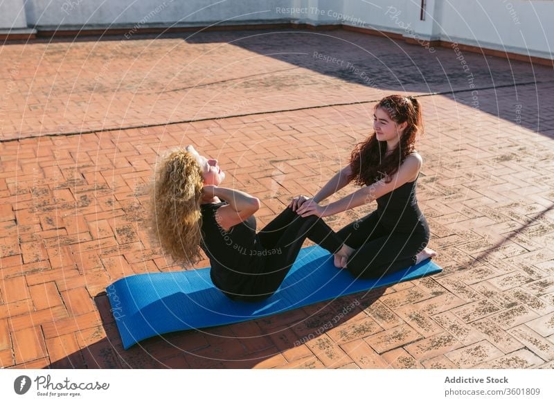 Women practicing partner yoga on rooftop women together terrace practice pose position core balance support acro yoga mother daughter lifestyle harmony wellness