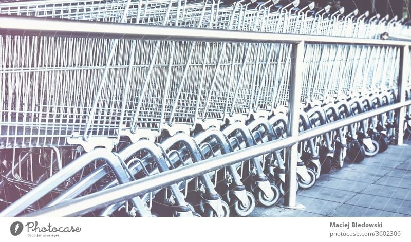 Row of empty shopping carts. supermarket retail row trolley store buy basket instagram effect business grocery consumerism metallic purchase chrome object