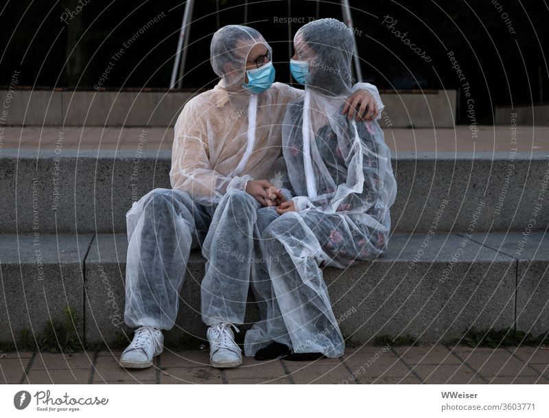 Couples cuddling in protective suits and masks Love corona Protection Protective clothing Mask proximity hug Safety sure Absurd Cuddling detachment pandemic