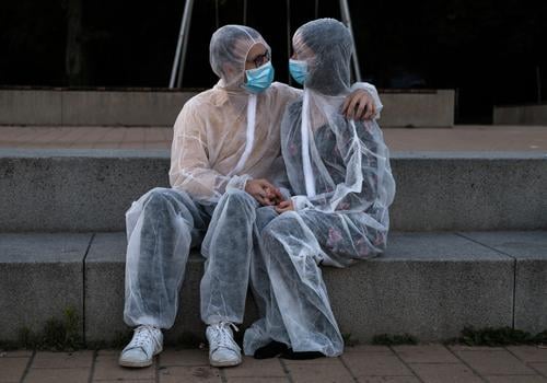 Couples cuddling in protective suits and masks Love corona Protection Protective clothing Mask proximity hug Safety sure Absurd Cuddling detachment pandemic