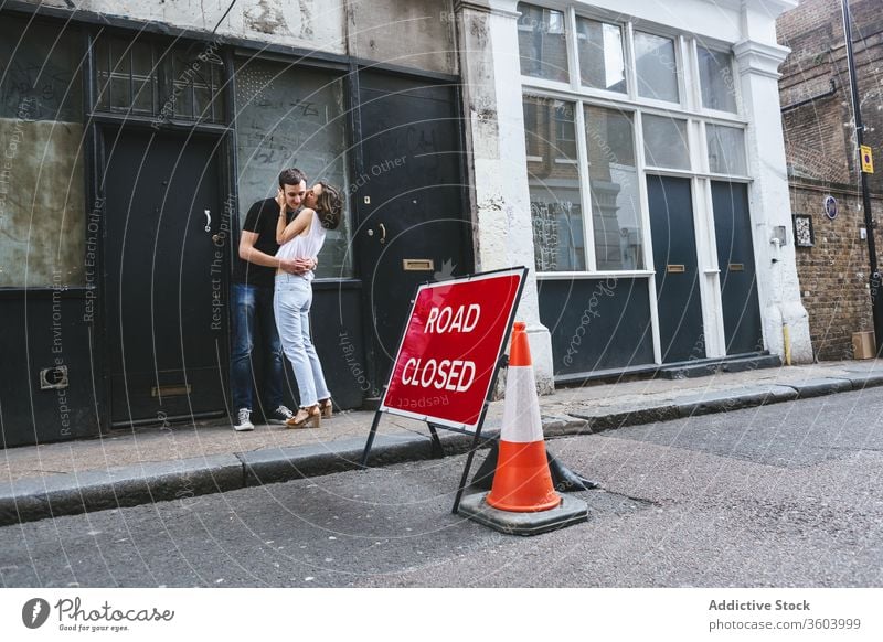 Cheerful couple hugging and kissing on street stroll city tender shabby building roadside london england united kingdom date together embrace love relationship