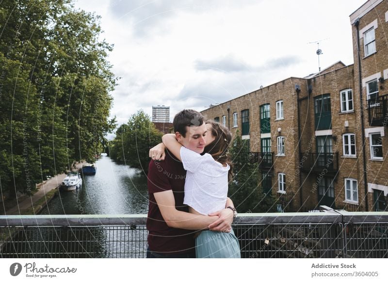 Loving couple hugging on bridge together embrace love relationship romantic city london tender england united kingdom date affection happy young cloudy fence